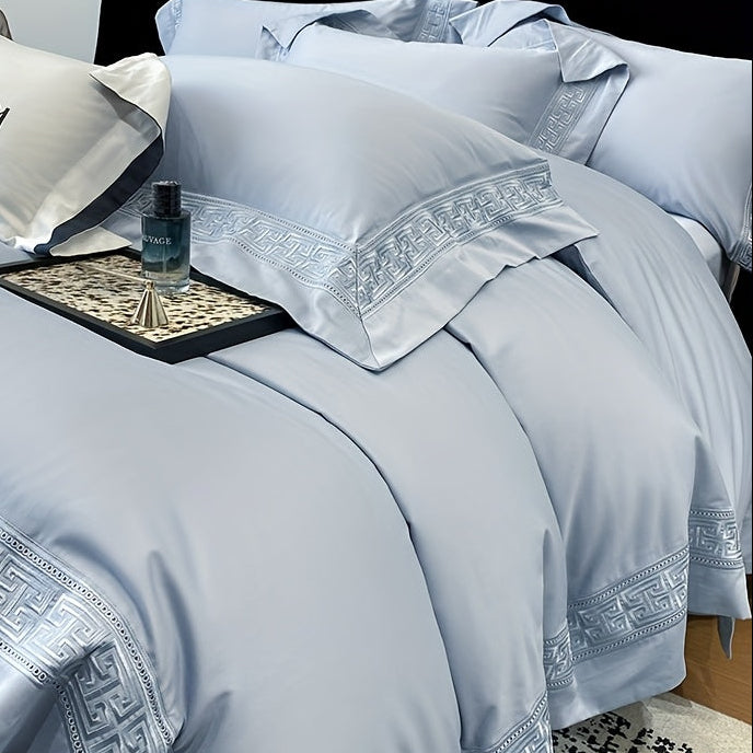 Luxury light blue bedding set with decorative patterns on a bed.