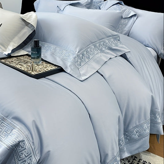 Luxury light blue bedding set with decorative patterns on a bed.