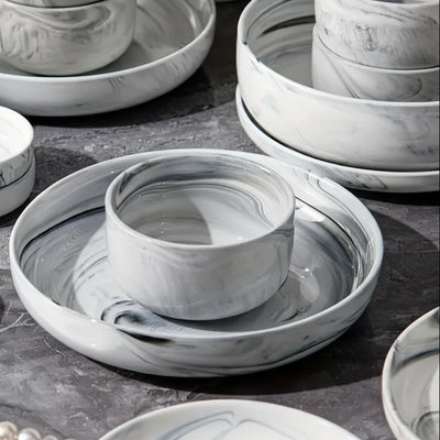 Set of marble-patterned ceramic dishes on a dark surface