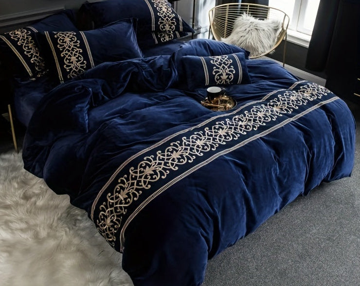 Navy blue bedding set with gold embroidery on a bed in a bedroom.